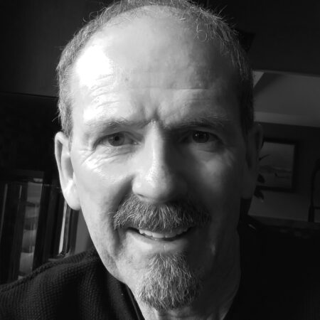 A photo of author Danial Neil. He is a white man with a moustache and goatee.