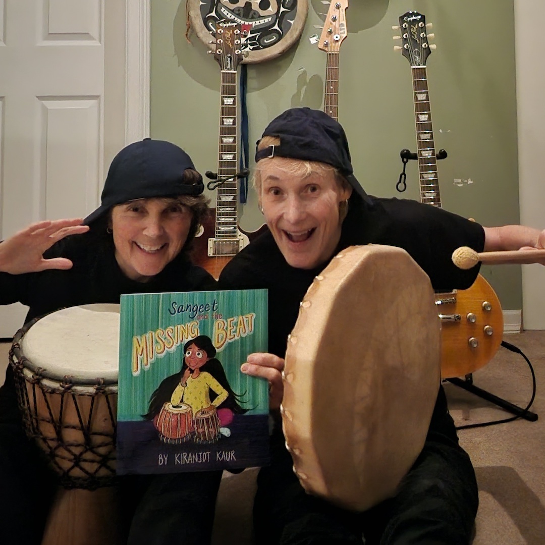 Lori and Cheryl Ann from Rebel Mountain Press with a copy of Sangeet and the Missing Beat and a handheld drum.