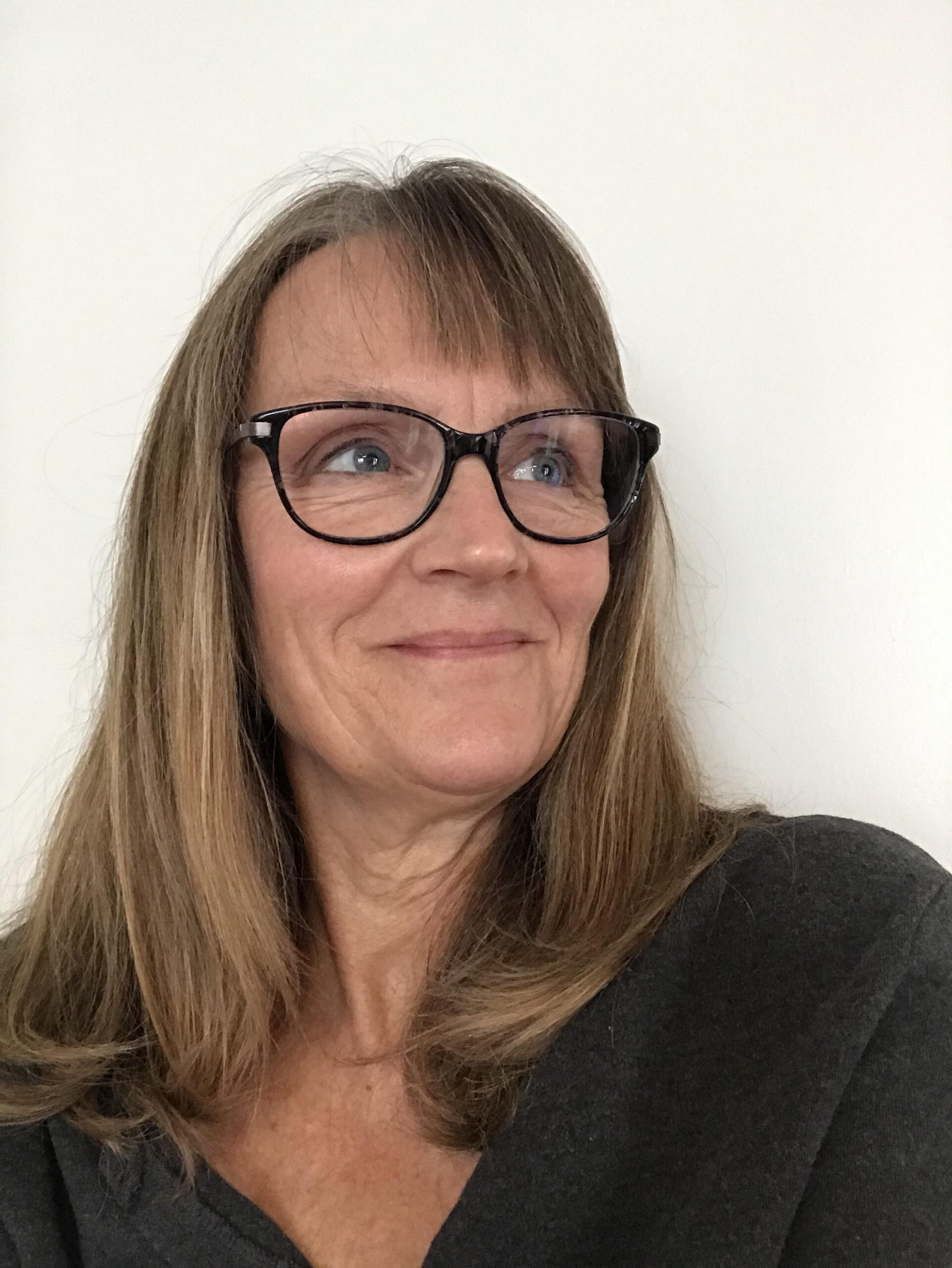A photo of writer Nancy Hundal. She's a light-skinned woman with medium length dark blonde hair, and wears black-rimmed glasses.