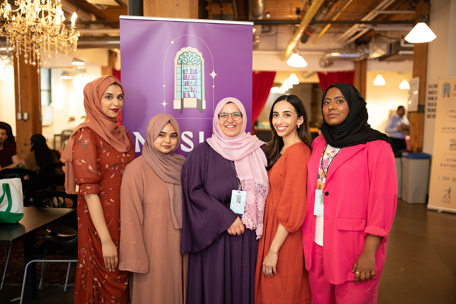 The organizers of the Muslim Literary Festival: five women standing in front of the MLF banner and smiling toward the camera.