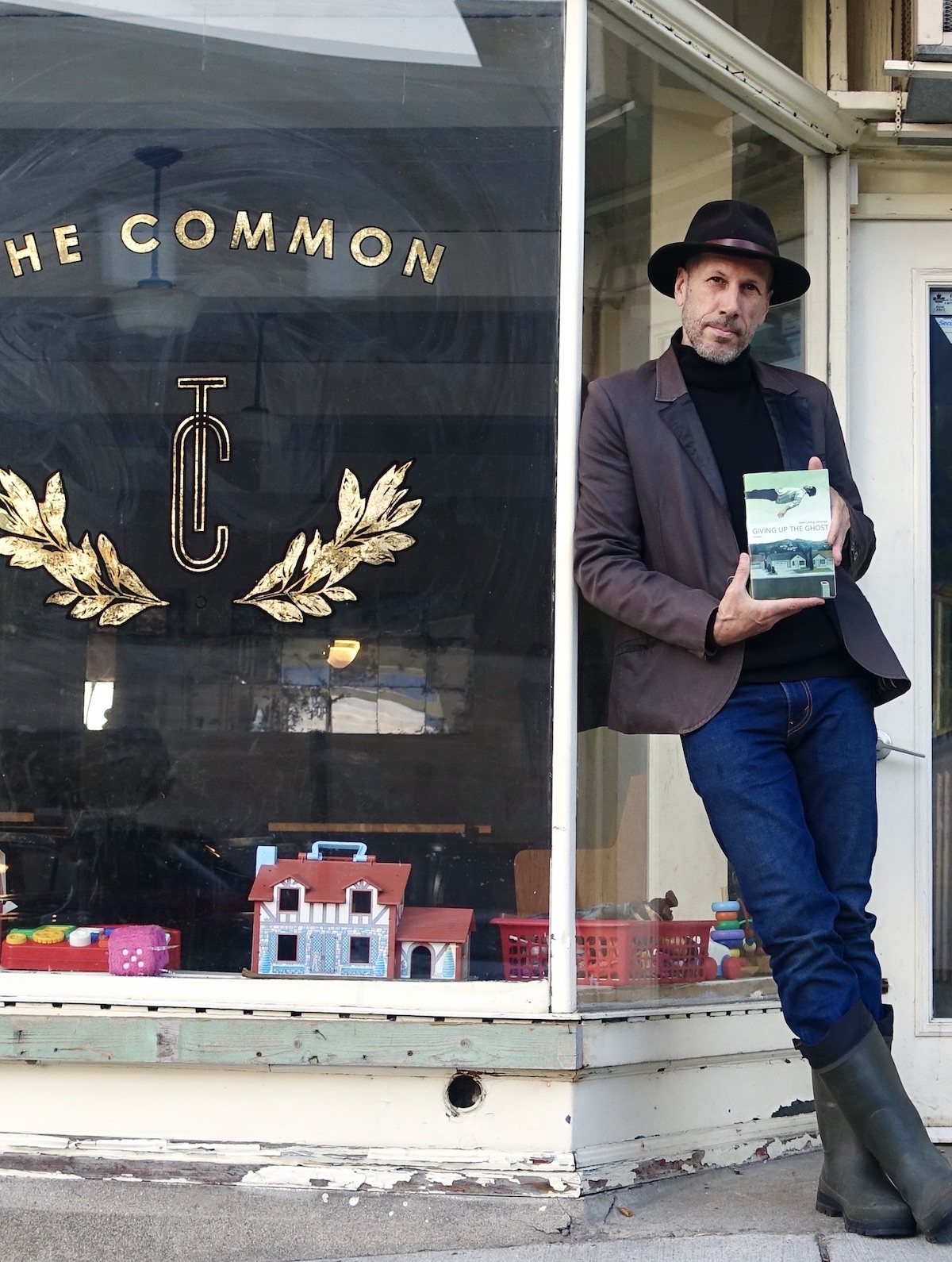 A photo of writer Adam Lindsay Honsinger next to the front window of The Common cafe in Guelph.