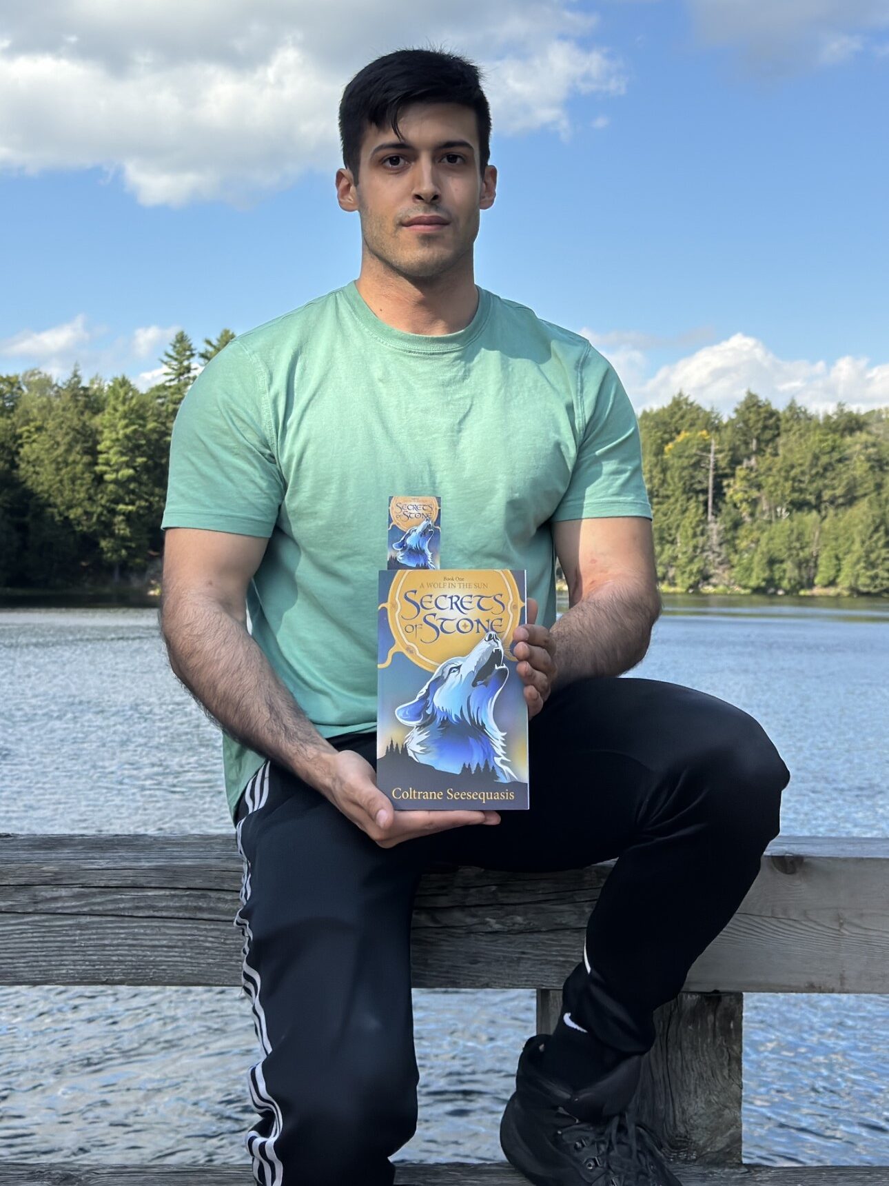 Coltrane Seesequasis in Gatineau Park on Bridge Lac Meech, holding a copy of Secrets of Stone.