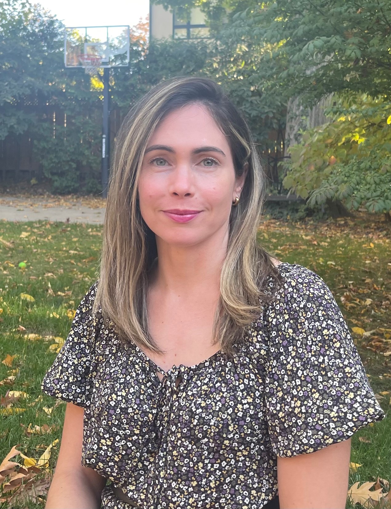 Photo of Stephanie Cesca, a light skin-toned woman with medium-length blonde hair. She is standing in an area with trees in the background.
