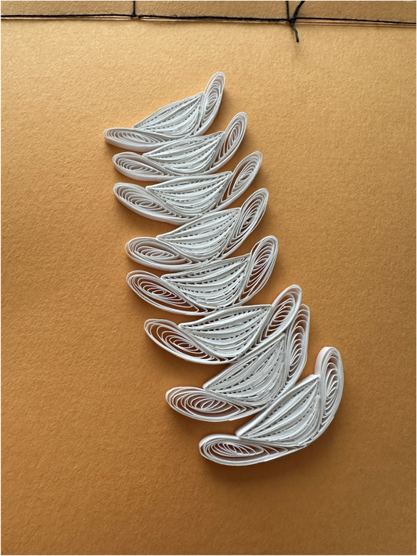 The same paper vertebrae from before but multiplied - eight stacked atop another on the light brown background.