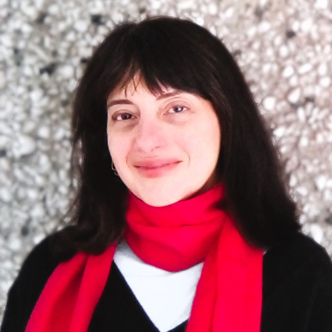 A photo of writer Rebecca Papucaru. She is a light skin toned woman with dark, straight hair cut into bangs, wearing a red scarf wrapped around her neck, over a white shirt and black sweater.