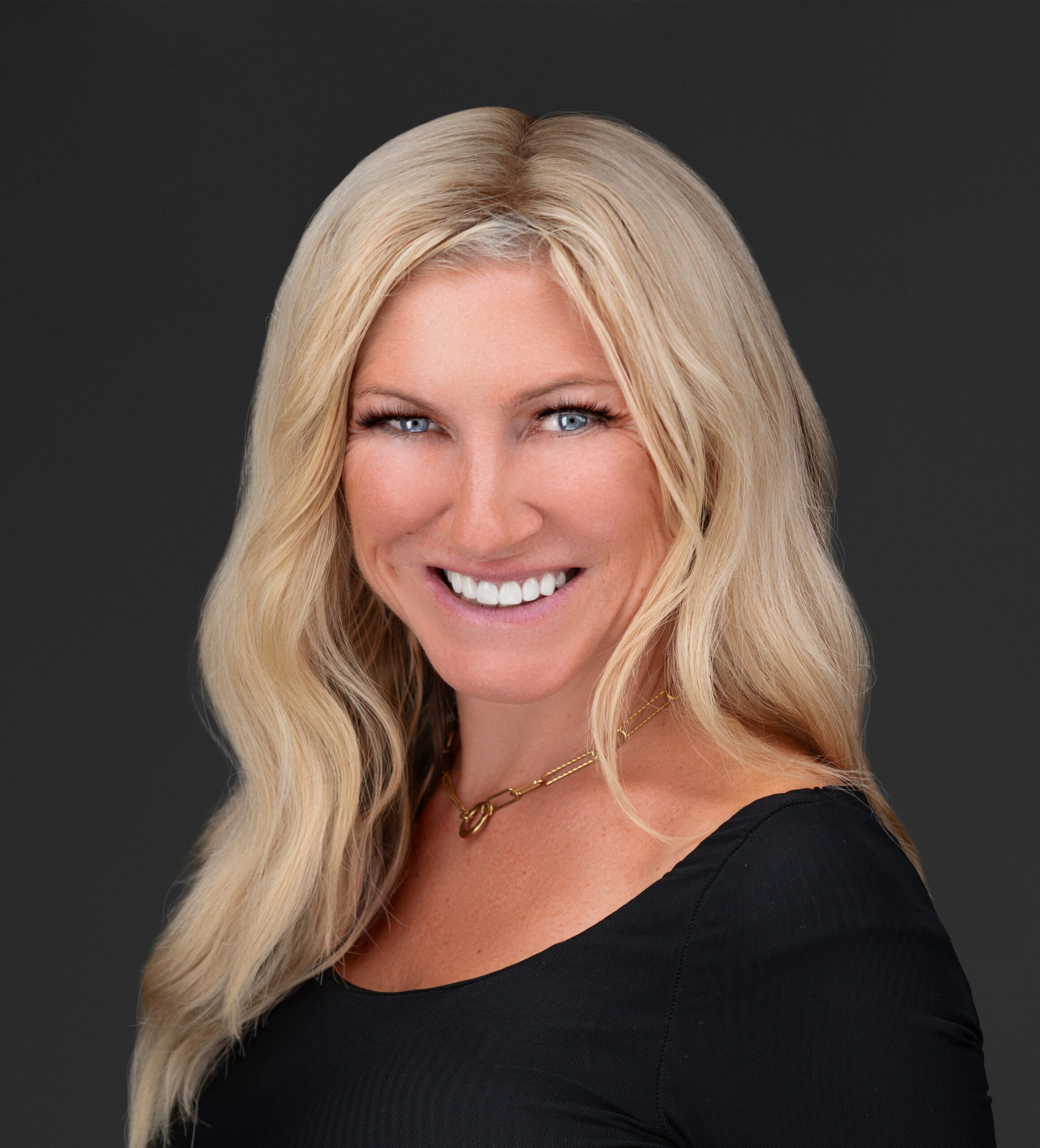 A close-up photo of Joanna Cockerline. She is a light-skin-toned woman with long blonde hair and blue eyes. She is smiling into the camera. 