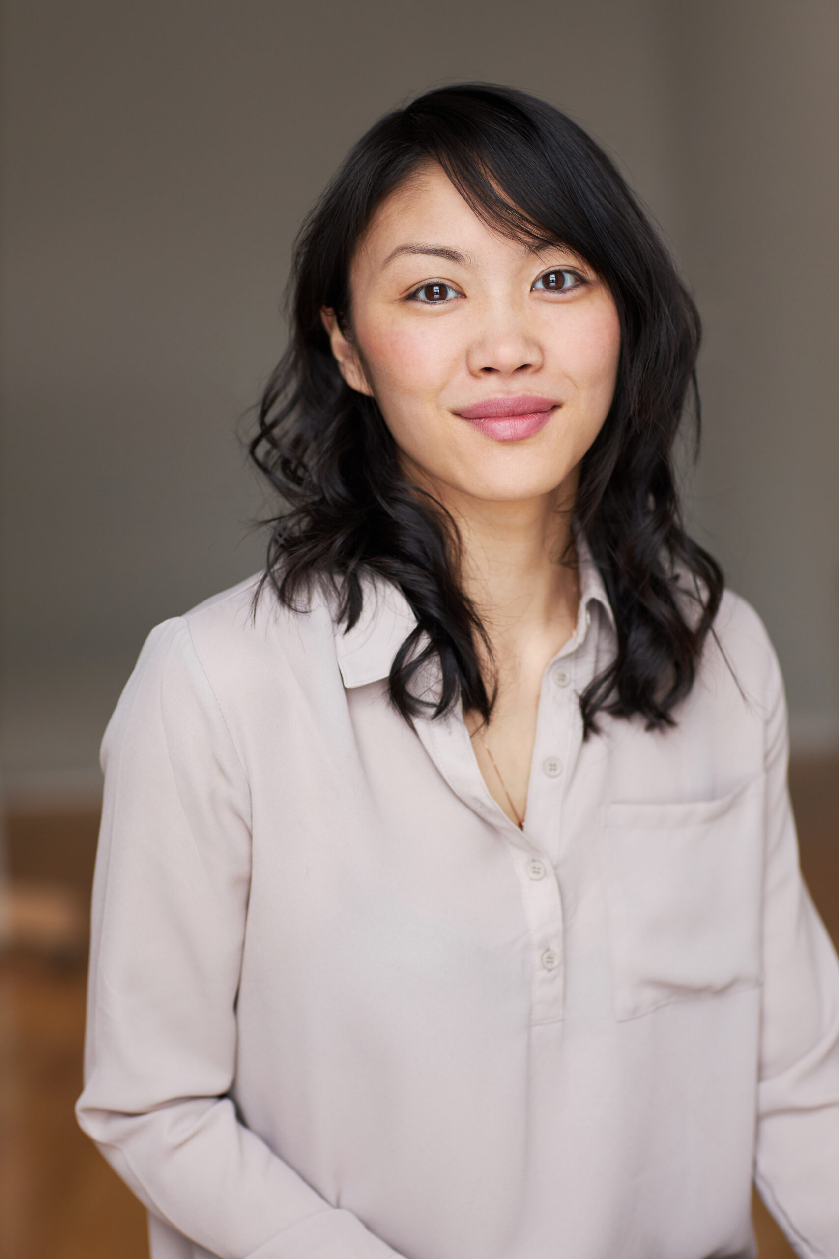 A photo of Gillian Sze. She is woman of Asian descent with shoulder-length dark brown hair and brown eyes. She is wearing a light pink collared shirt and smiling into the camera. 